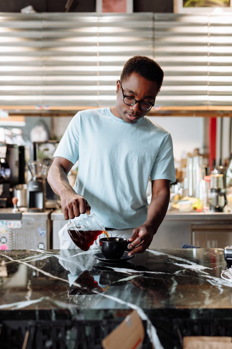 A Man In White Shirt Pouring Coffee On A Cup