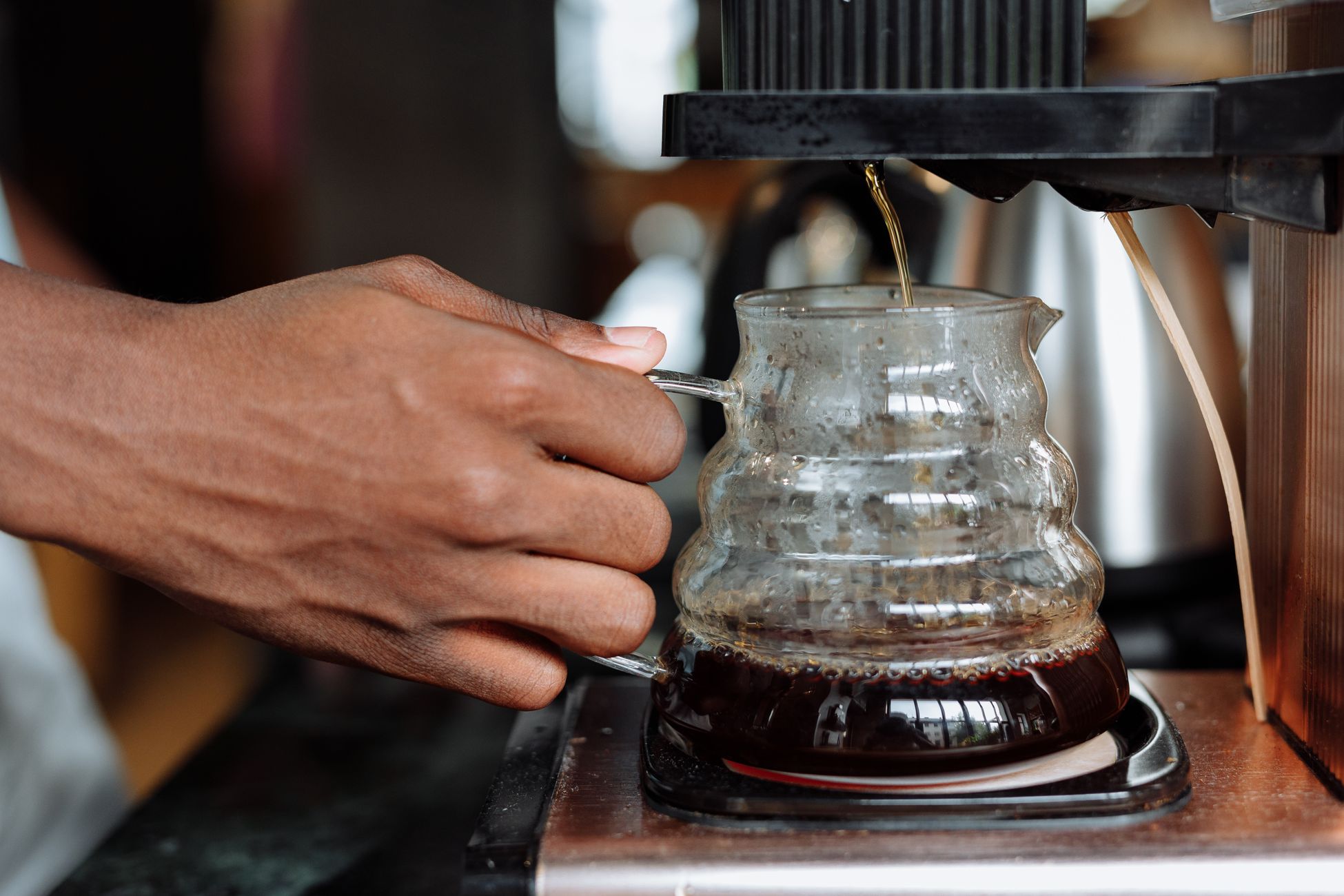 A person brewing coffee using a glass carafe and coffee machine.