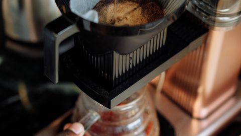 Pour over coffee preparation with hand pouring hot water over ground coffee in a filter.