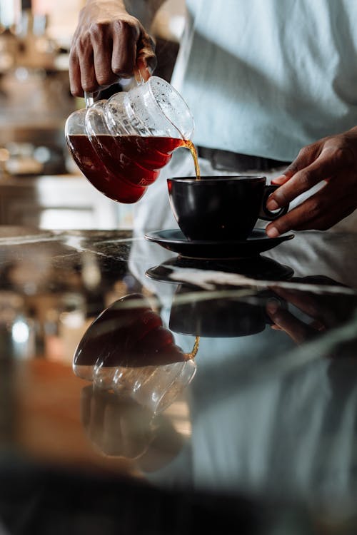 Free A Person Pouring Brewed Coffee in a Cup Stock Photo