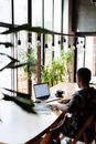 Man in Black and White Floral Shirt Sitting at Table Using Laptop Computer