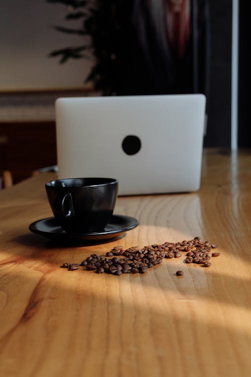 Coffee Beans on a Wooden Table near Cup and Laptop