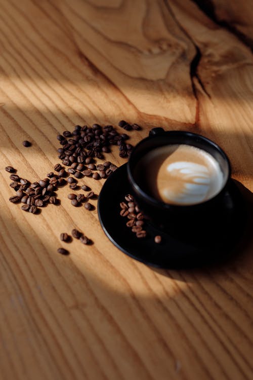 Coffee Beans and a Cup of Coffee on a Wooden Table
