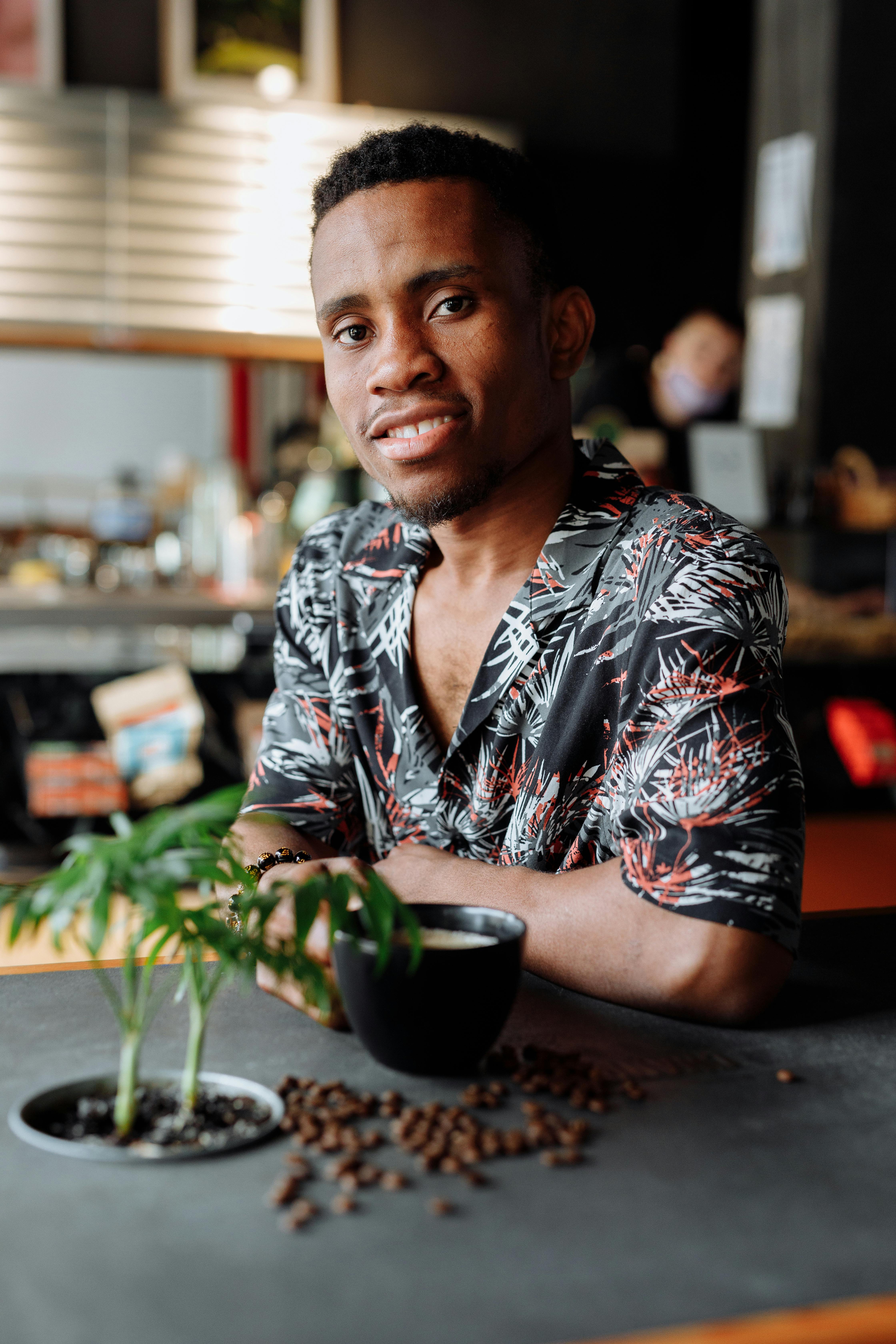 Portrait of a smiling African American man with coffee in a cafe setting, offering a warm atmosphere.