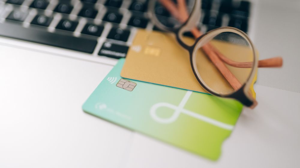 Close-up of eyeglasses and credit cards on a laptop, emphasizing finance and technology.