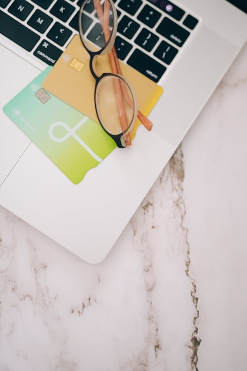 Free High-Angle Shot of Credit Cards and Eyeglasses on Laptop Keyboard  Stock Photo