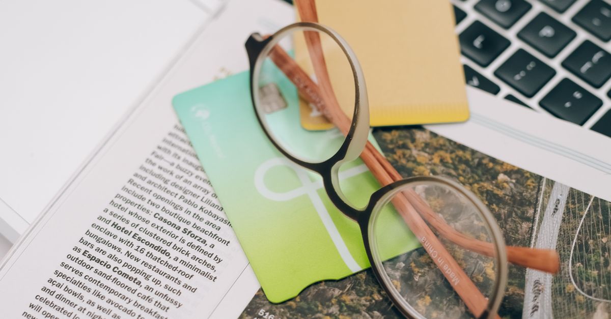 A sleek silver laptop sits open on a wooden desk with a green backdrop, illustrating a modern workspace.