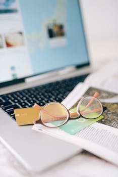 Close-up of eyeglasses and credit cards on a laptop, depicting a modern lifestyle scene.