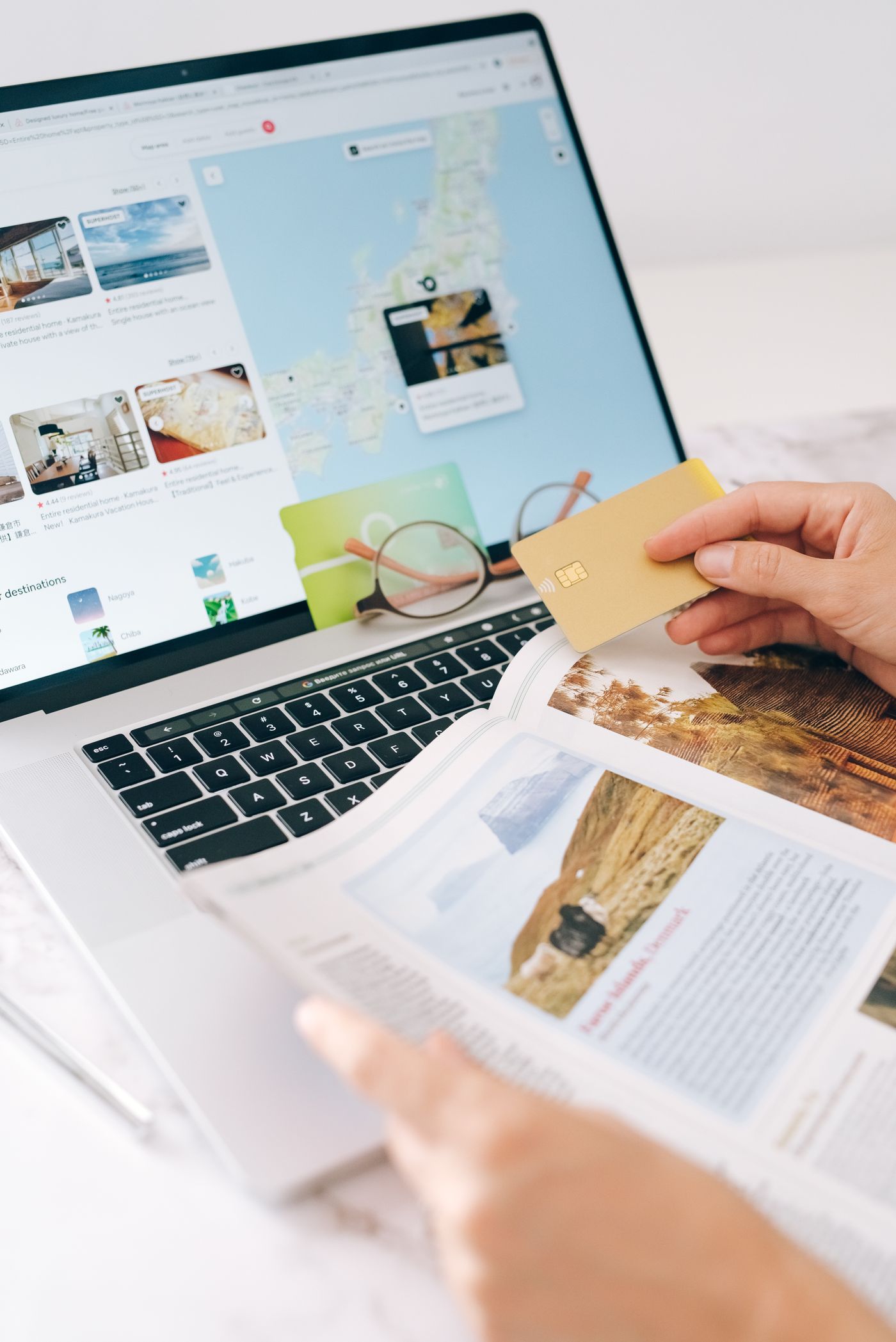 Person holding a credit card while using a laptop for online travel planning and booking