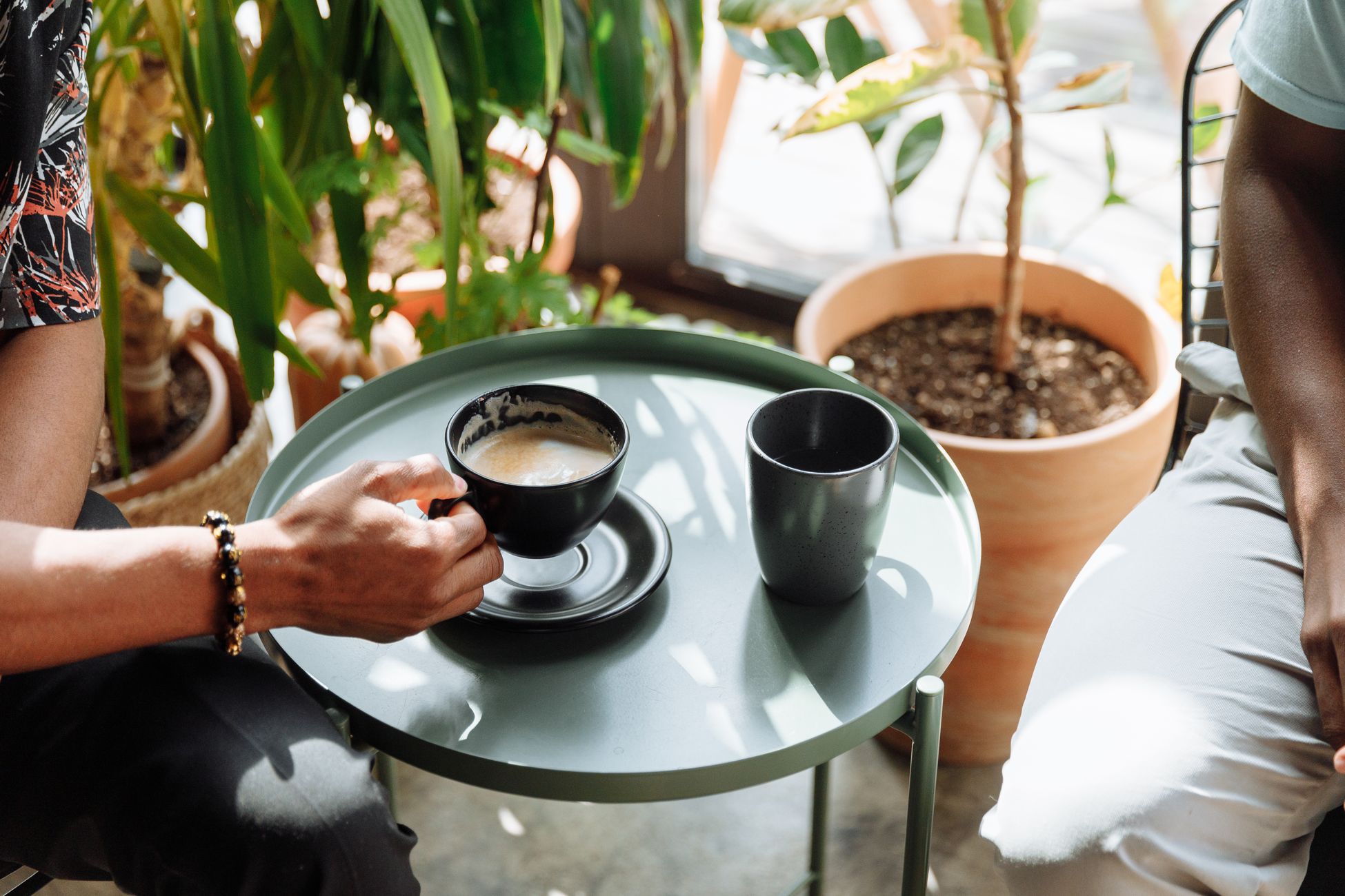 Cozy indoor setting with a coffee cup on a table amidst green plants.