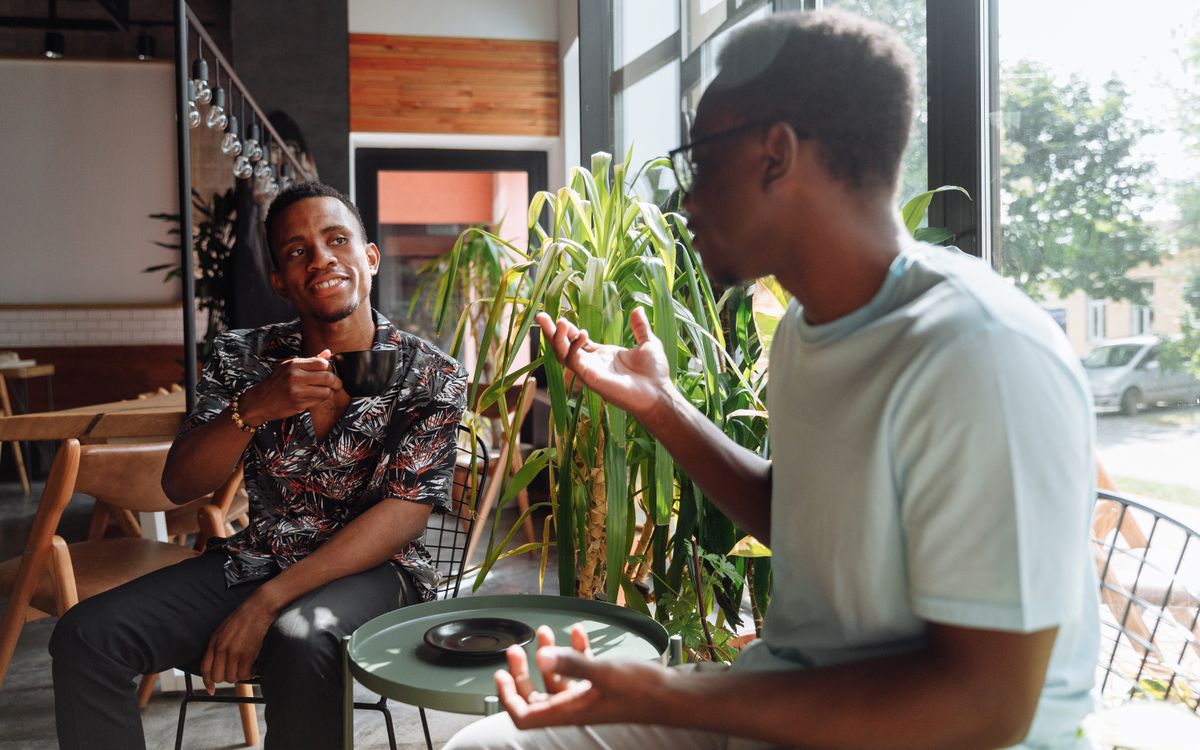 Two friends having a lively conversation over coffee in a cozy coffee shop setting.