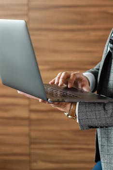 Close-up of a businessman using a laptop indoors, focused on the typing action.