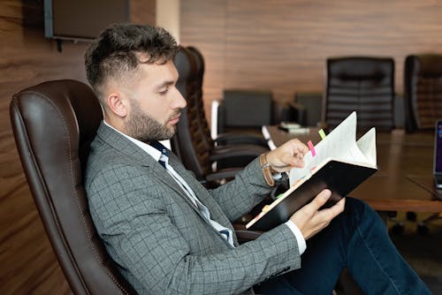 Free Man Sitting on the Office Chair while Holding a Book Stock Photo