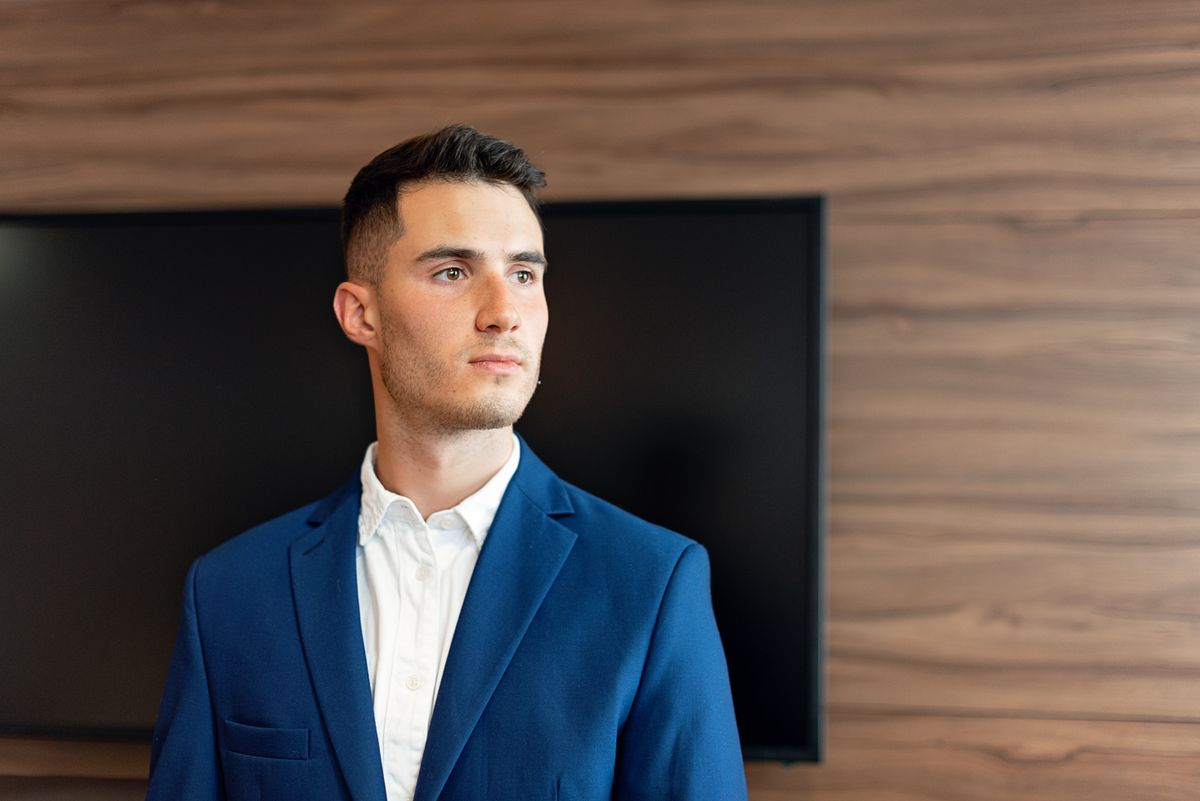 Confident young businessman in a blue suit posing in a modern office environment