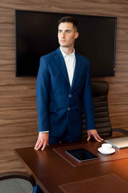 Free Professional man in a blue suit standing confidently in a modern office. Stock Photo