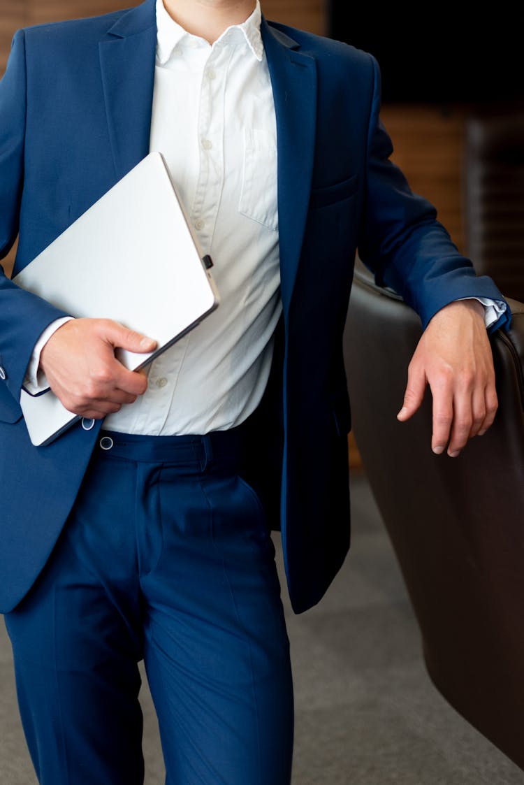 A Person In Blue Suit Carrying A Laptop