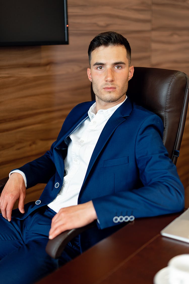 Photo Of A Man In A Blue Suit Sitting On A Chair