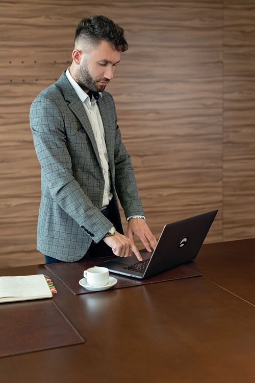 Free Professional man in suit working on a laptop at a modern office desk. Stock Photo