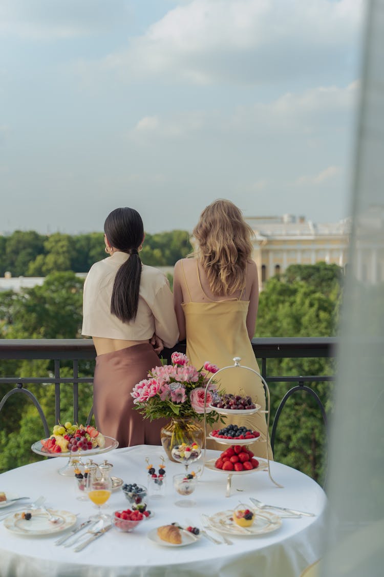 A Back View Of Women Standing At The Balcony