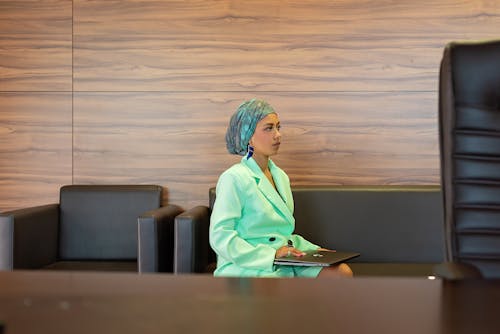 Woman in Green Blazer With Turban Sitting On a Couch With Laptop