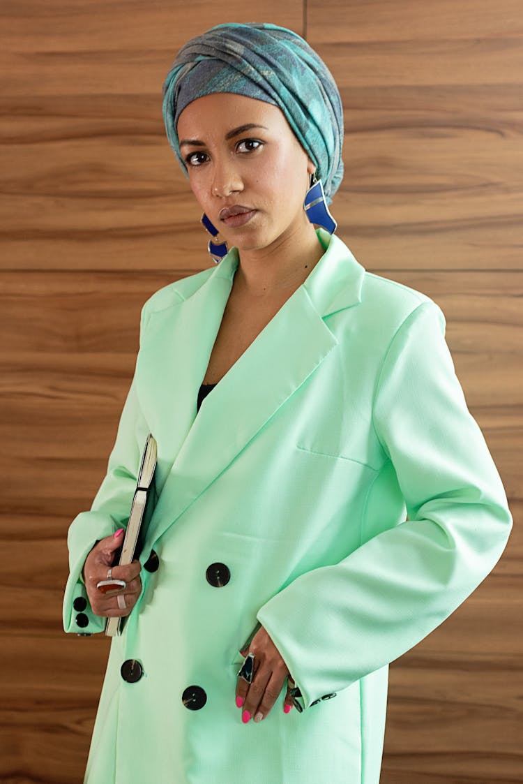 A Woman Wearing A Green Blazer And Headscarf