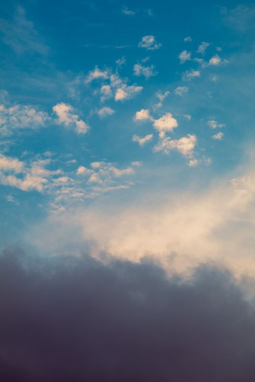 Free Stunning view of a blue sky with scattered white clouds against a dark cloud backdrop. Stock Photo