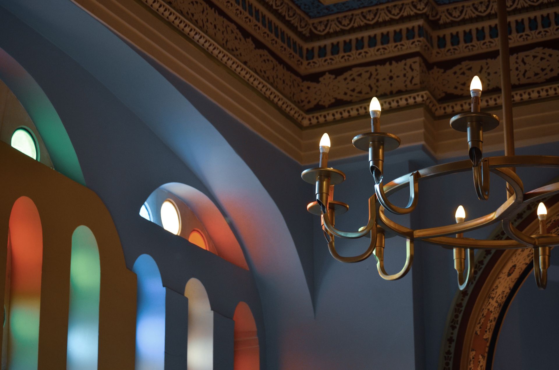 Colorful stained glass and ornate ceiling with chandelier in a Turkish interior setting.