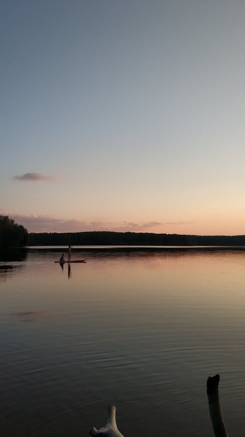 Person Standing on the Boat While Sailing in the Calm Body of Water 