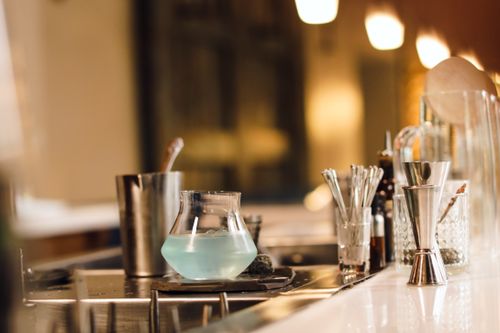 Free A modern bar countertop featuring cocktail preparation tools and a glass with a blue drink. Stock Photo
