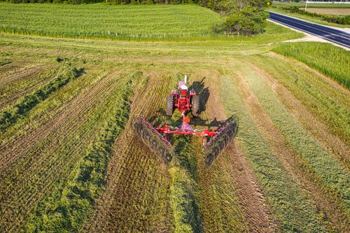 Free Drone captures red tractor working in lush Minnesota field during summer. Stock Photo