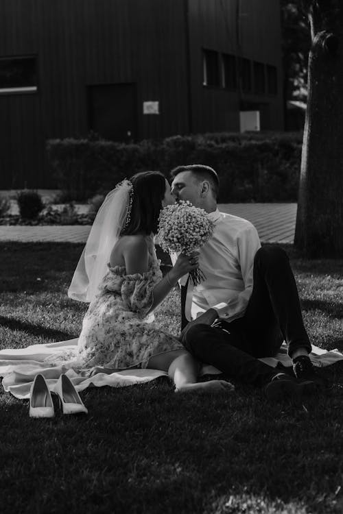 Grayscale Photo of Man and Woman Sitting on Grass Field