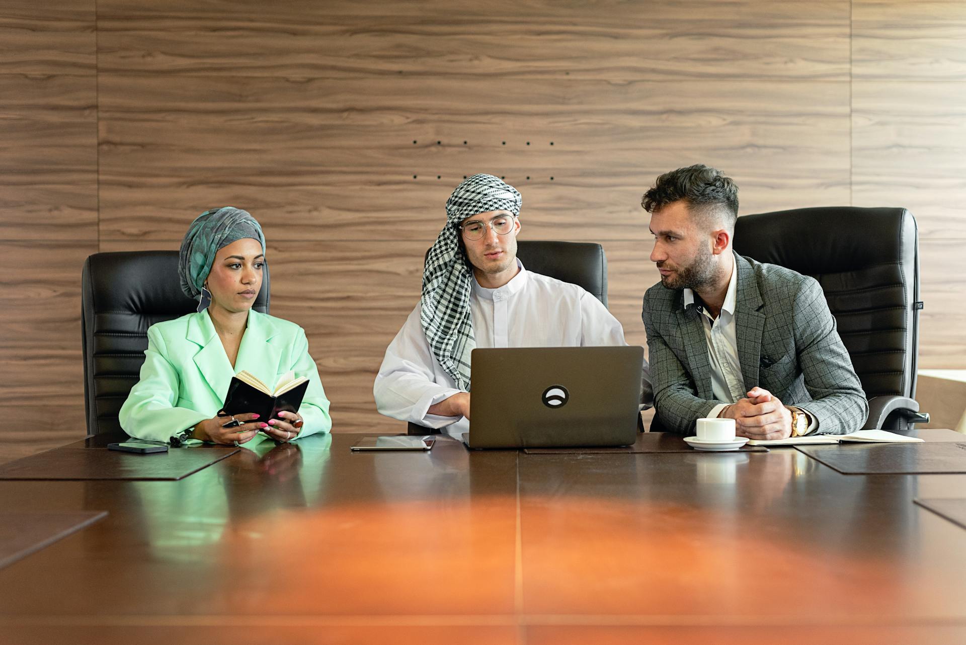 Three professionals in a diverse, multicultural meeting setting discussing business planning.