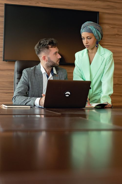 Free Professional meeting between colleagues in an office discussing work on a laptop. Stock Photo