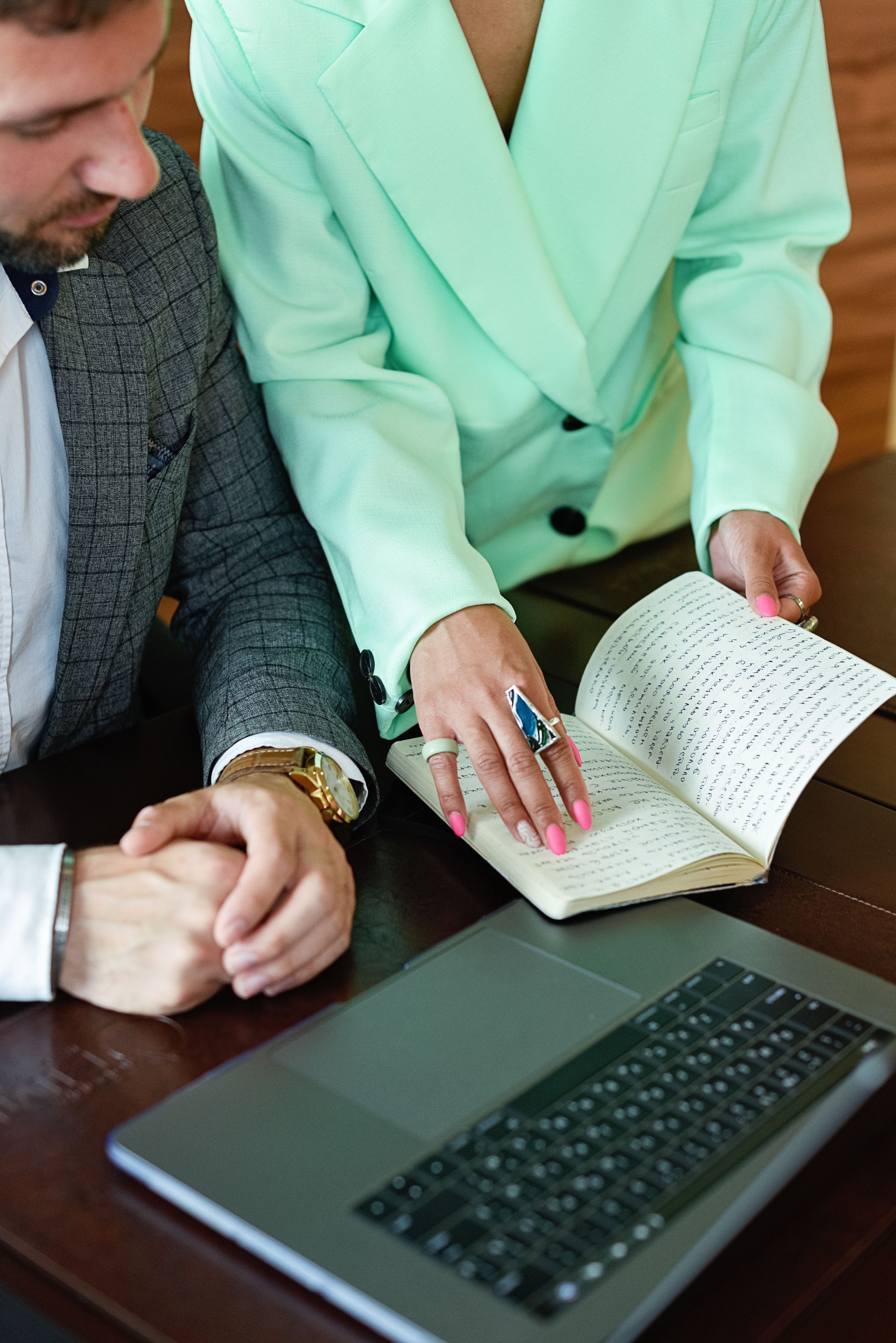 Professional duo reviewing notes in a business meeting with a laptop.