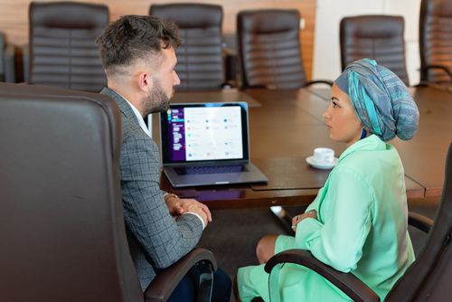 Free A man and woman discussing business plans in a conference room with a laptop. Stock Photo