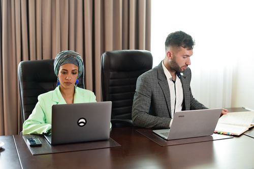 Free Business meeting with a diverse team discussing work at a conference table, using laptops. Stock Photo