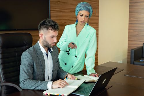 Free A Muslim woman and a Caucasian man collaborating in a modern office setting. Stock Photo