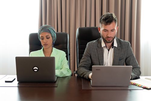 Free Two professionals working together on laptops in a modern office environment. Stock Photo