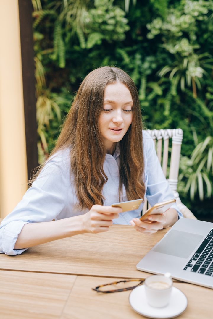 A young woman shopping online with her phone and a card