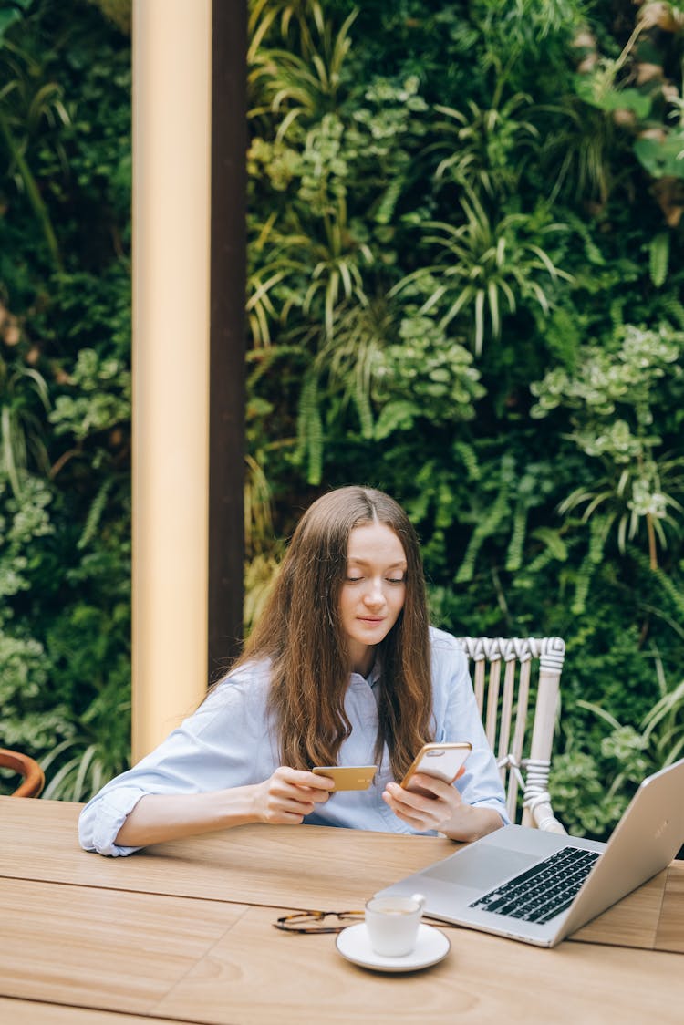 A Woman Holding Her Mobile Phone And Credit Card