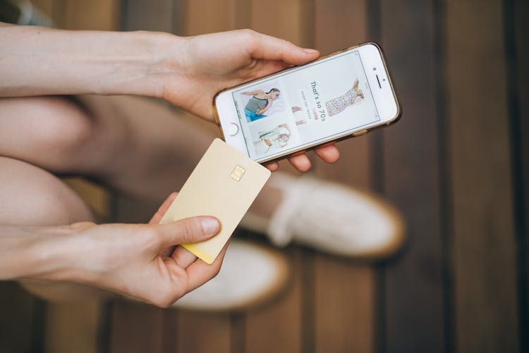 Person Holding An IPhone And A Card 