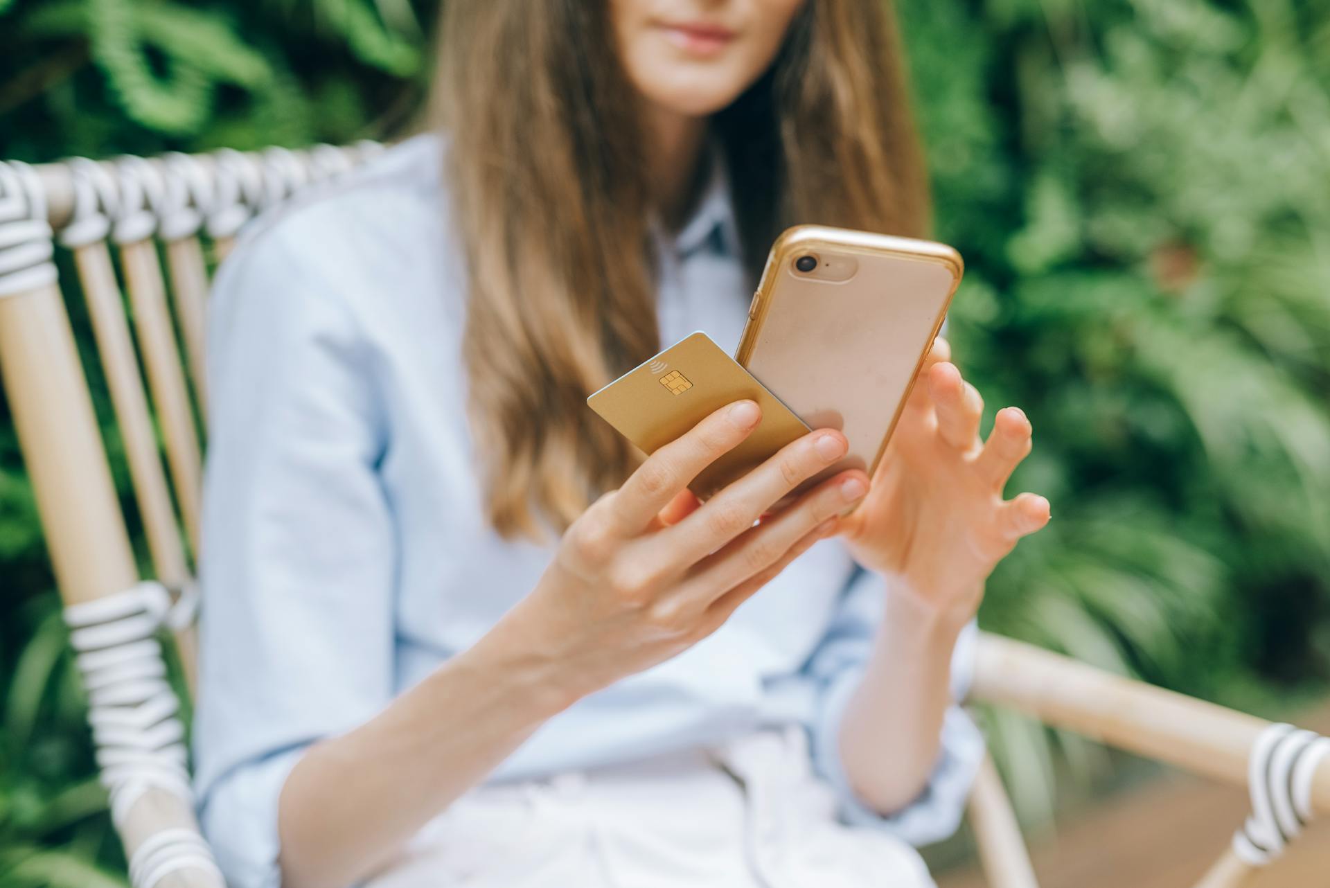 A woman making an online purchase using a smartphone and credit card outdoors.