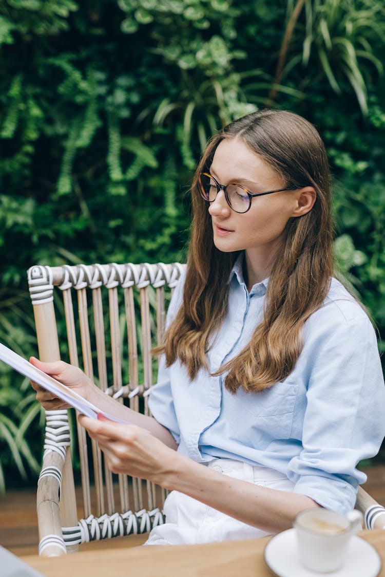 A Woman Sitting On A Wooden Armchair Reading