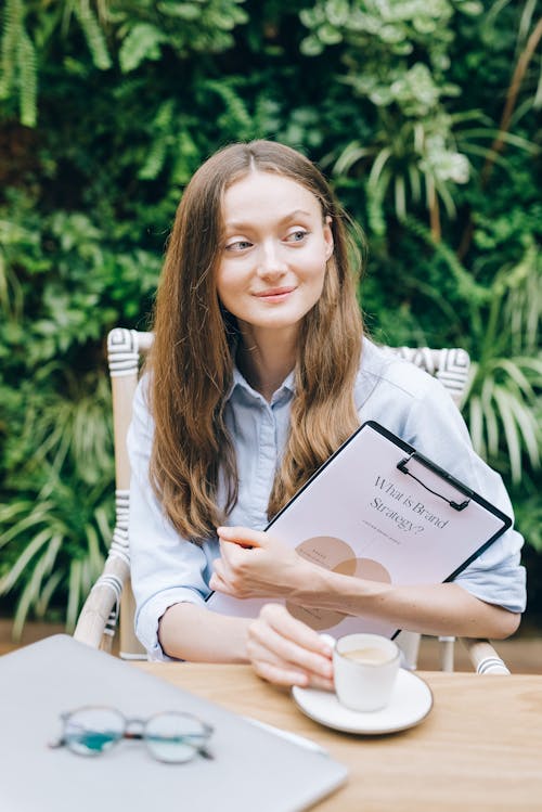 Woman Wearing Long Sleeve Shirt Holding a Cup of Coffee