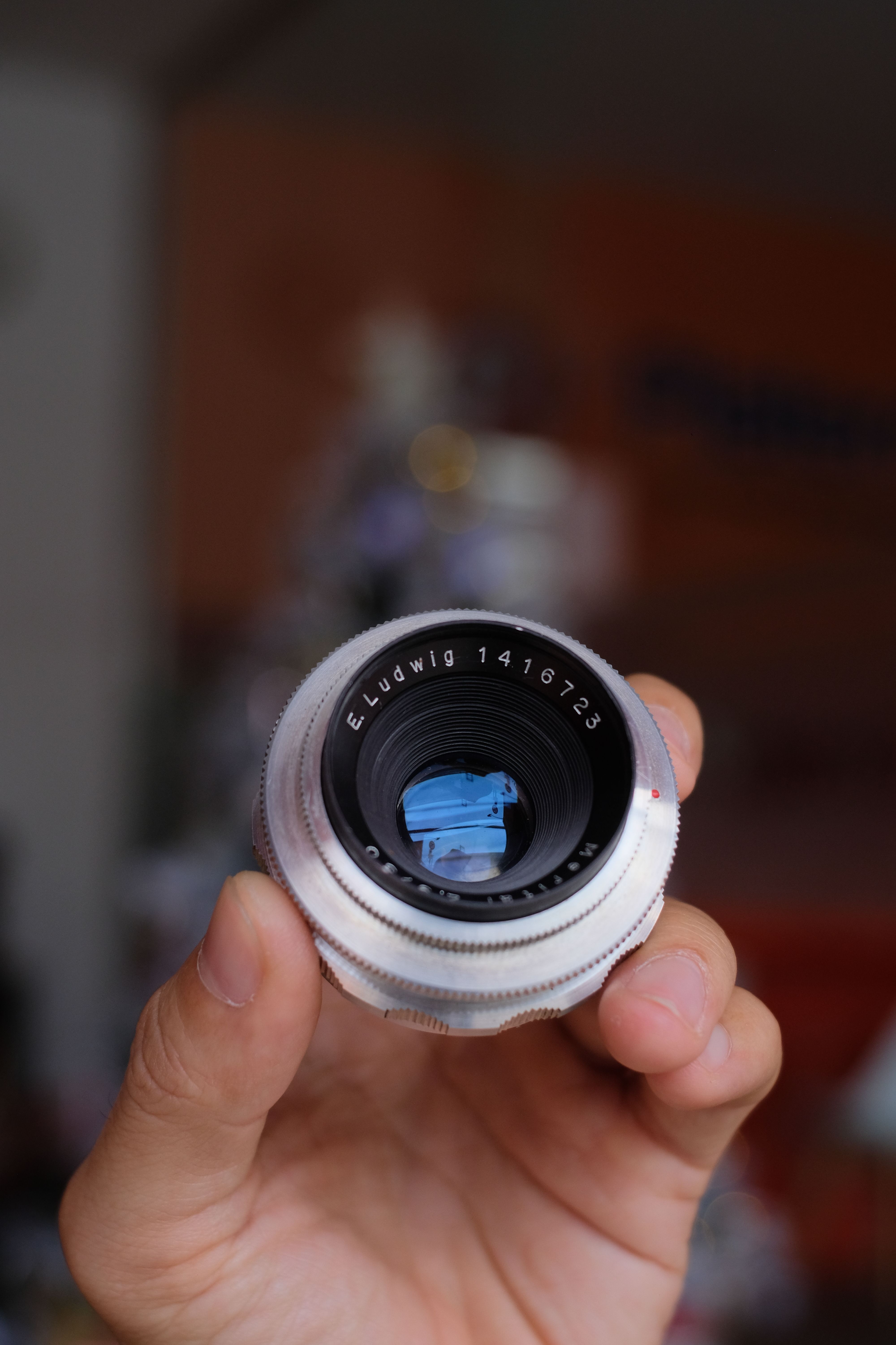 Detailed view of a hand holding a classic vintage camera lens in focus.