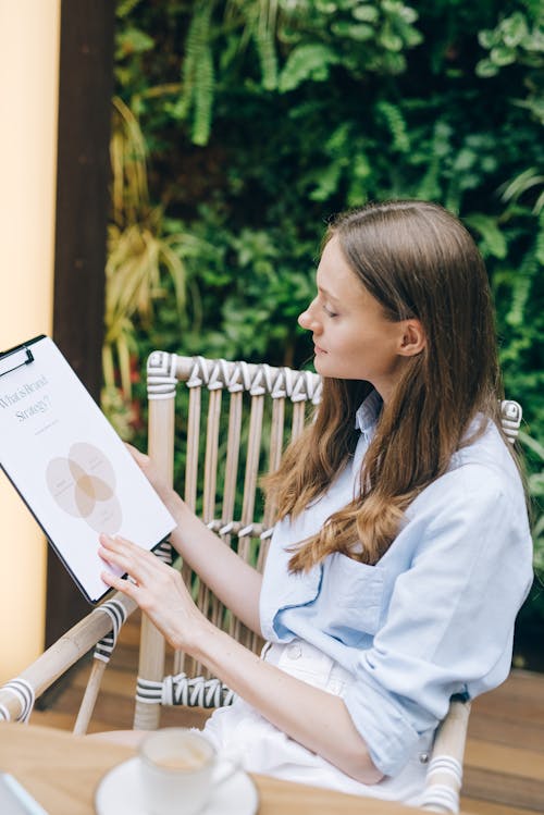 Free Woman Reading a Document on a Clipboard Stock Photo