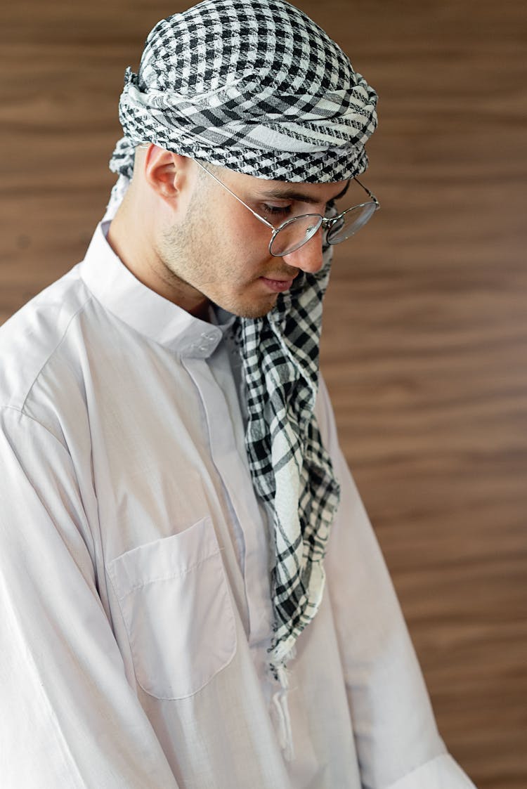 Man Wearing Headscarf And White Thobe Looking Down