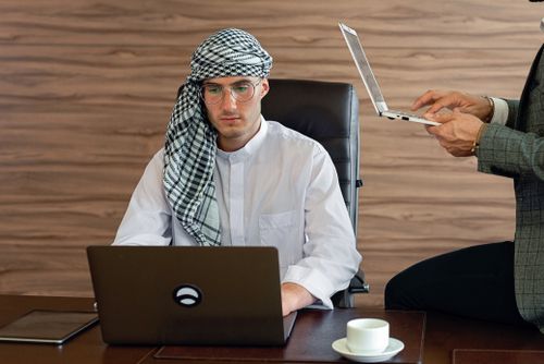 Free Middle Eastern businessman in office attire focused on work with laptops. Stock Photo