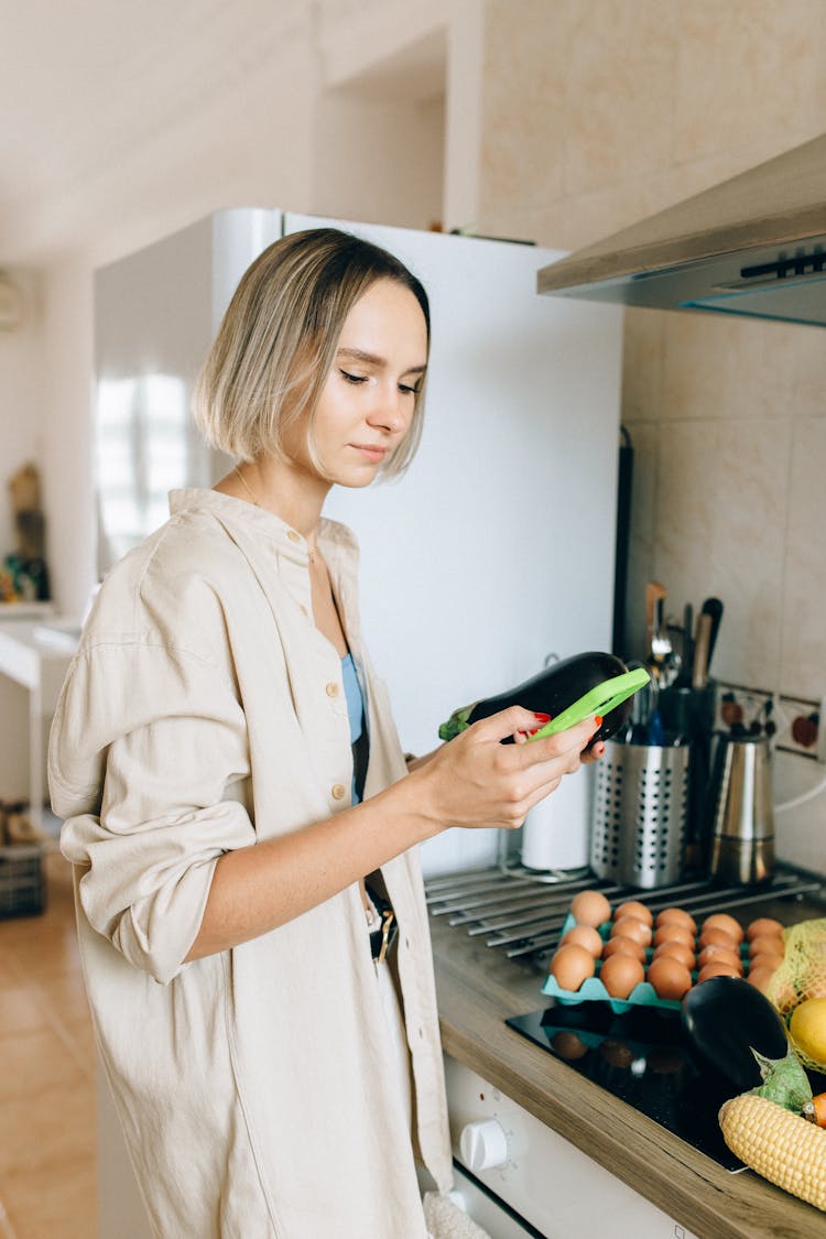 A Woman Using Her Mobile Phone In The Kitchen