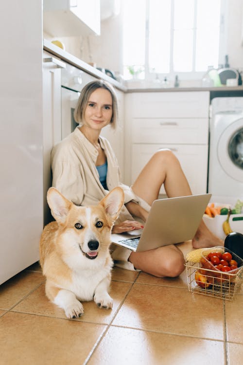 A Woman Sitting Near a Corgi Dog